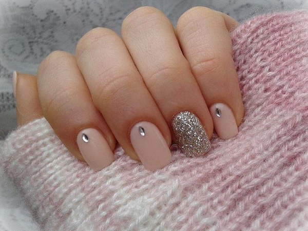 Manucure beige avec paillettes, strass sur ongles courts à la base, frottés, motif. Une photo