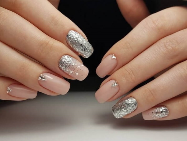 Manucure beige avec paillettes, strass sur ongles courts à la base, frottés, motif. Une photo