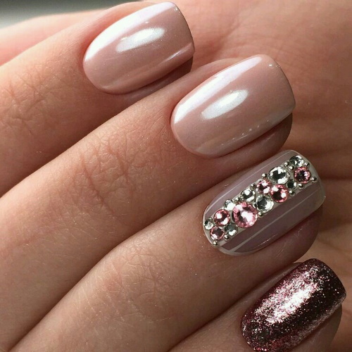 Manucure beige avec paillettes, strass sur ongles courts à la base, frottés, motif. Une photo